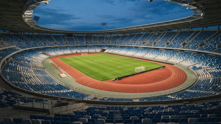Prázdný fotbalový stadion s modrobílými sedačkami a atletickým oválem