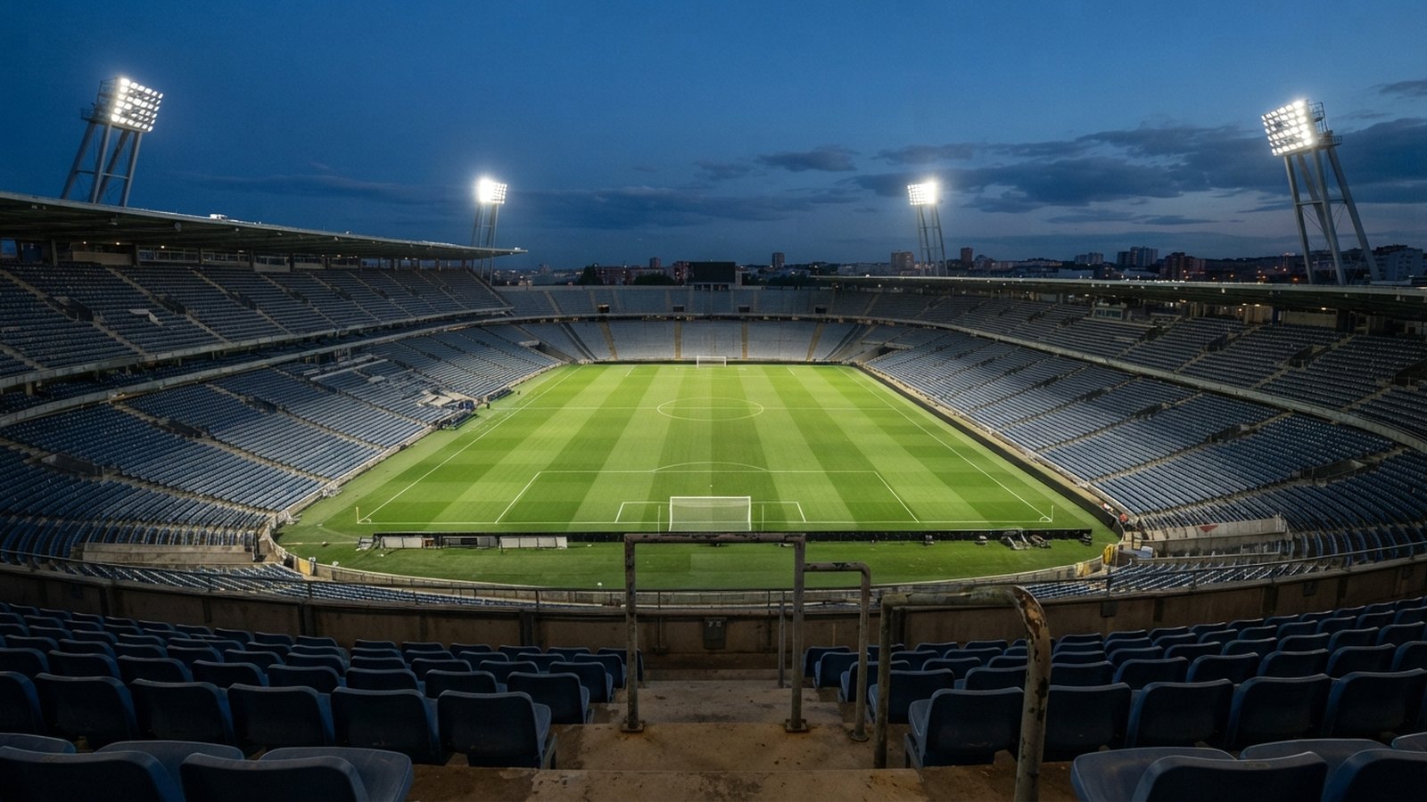 Prázdný fotbalový stadion za soumraku s rozsvícenými reflektory