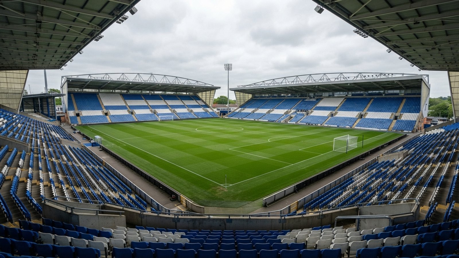 Prázdný fotbalový stadion s modrobílými sedačkami a čtyřmi tribunami